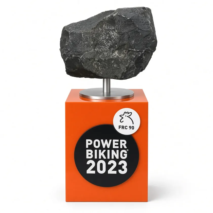 Trophäe aus Naturstein auf orangefarbenem Sockel mit Logo eines Radsport-Events